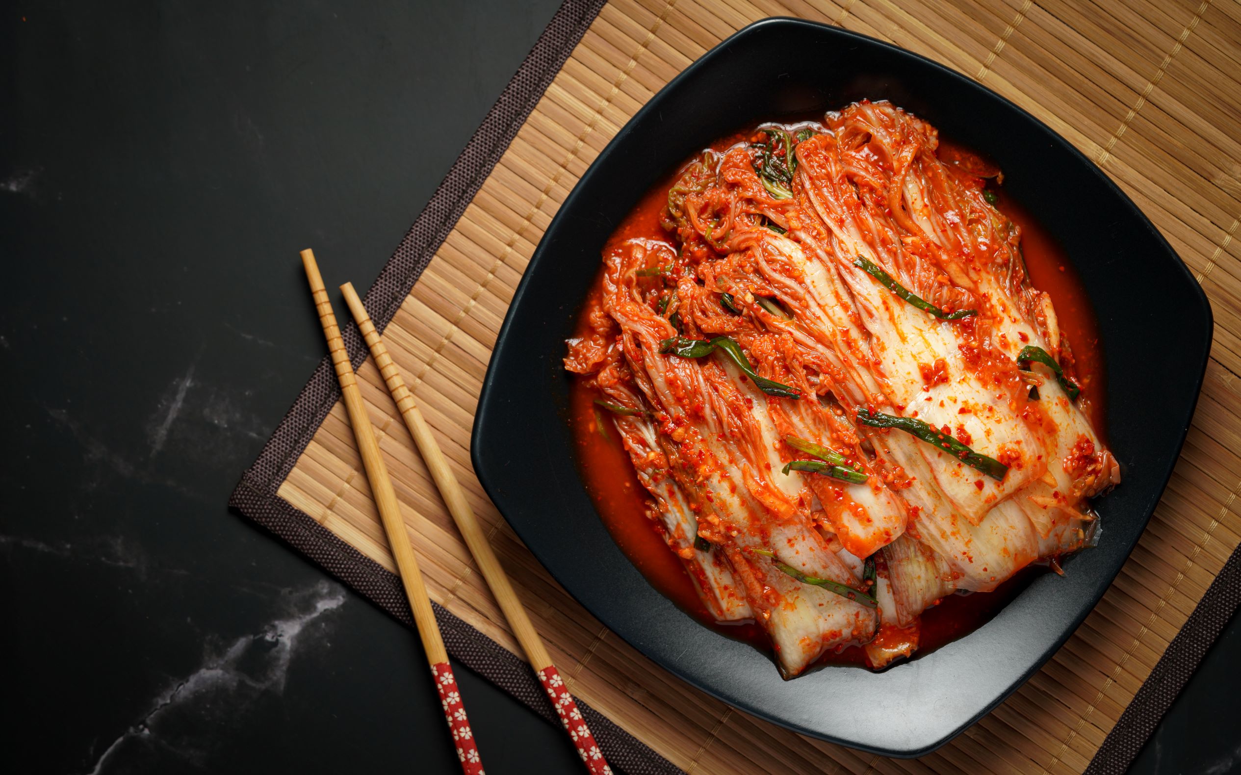 Korean kimchi. Korean traditional cabbage kimchi on a white plate viewed  from above. Wood deck background, closeup Stock Photo - Alamy